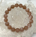 Natural peach moonstone 10mm gemstone bracelet from World Wide Gems Minerals Beads, featuring smooth, round peach-colored stones.