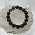 Smoky Quartz 12mm round bracelet by World Wide Gems Minerals Beads, featuring polished smoky quartz beads on a stretchy cord.
