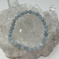 Two blue aquamarine 6mm round gemstone bracelets from World Wide Gems Minerals Beads, showcasing polished beads and adjustable cord.