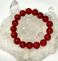 Carnelian 12mm round gemstone bracelet from WorldWideMinerals-beads featuring polished orange-red beads on elastic cord.
